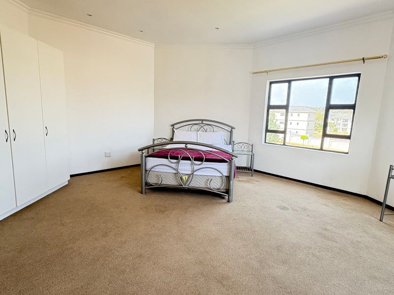 Spacious bedroom featuring built-in cupboards, carpeted flooring, and large windows providing natural light.