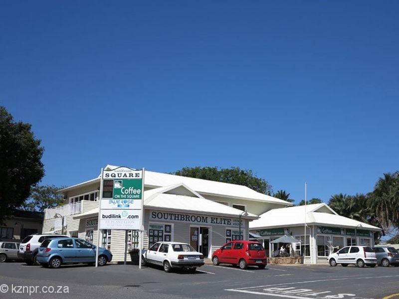 Front view of the Southbroom Square commercial property featuring multiple storefronts, signage, and an asphalt parking area.