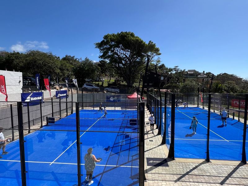 Well-maintained outdoor padel courts featuring blue synthetic surfaces, perimeter fencing, and integrated floodlighting for recreational use.