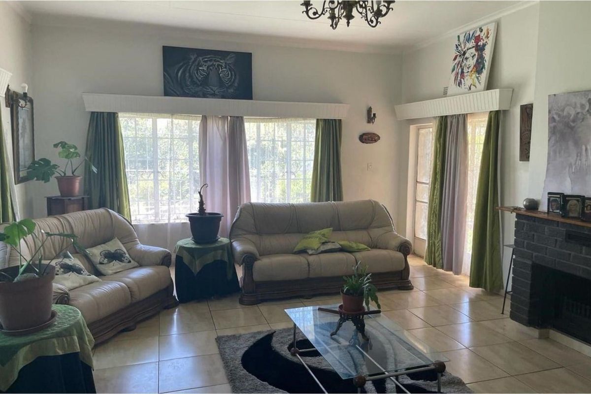 Spacious living room featuring tiled flooring, a brick fireplace, and large windows providing ample natural light.