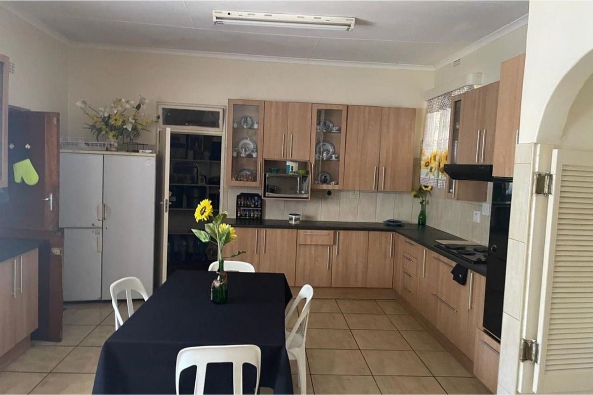 Functional kitchen featuring laminate cabinetry, built-in oven, hob, extractor fan, and tiled flooring, with convenient access to an adjoining scullery area.