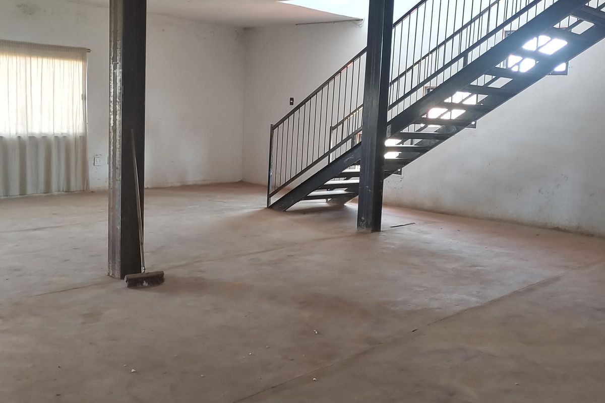 An expansive, open-plan living area featuring industrial-style steel support columns and a prominent steel staircase, offering a blank canvas for renovation.