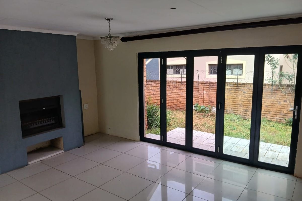 Spacious living area featuring tiled floors, a built-in fireplace, and large folding glass doors providing direct access to the rear garden.