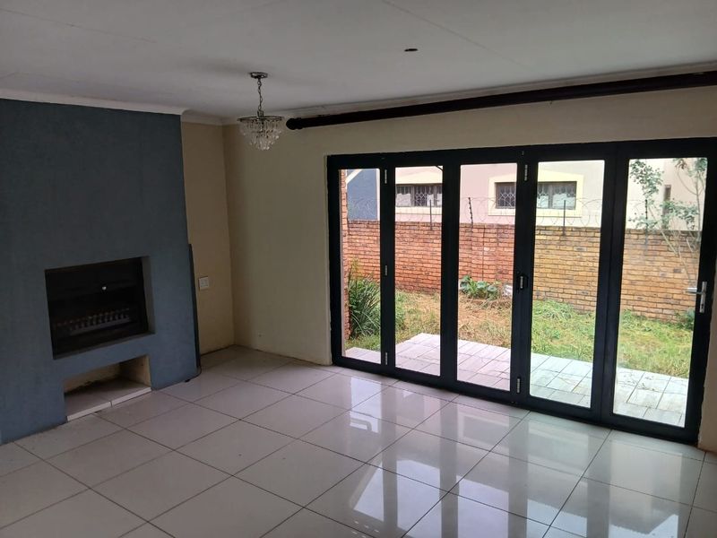 Spacious living area featuring tiled floors, a built-in fireplace, and large folding glass doors providing direct access to the rear garden.