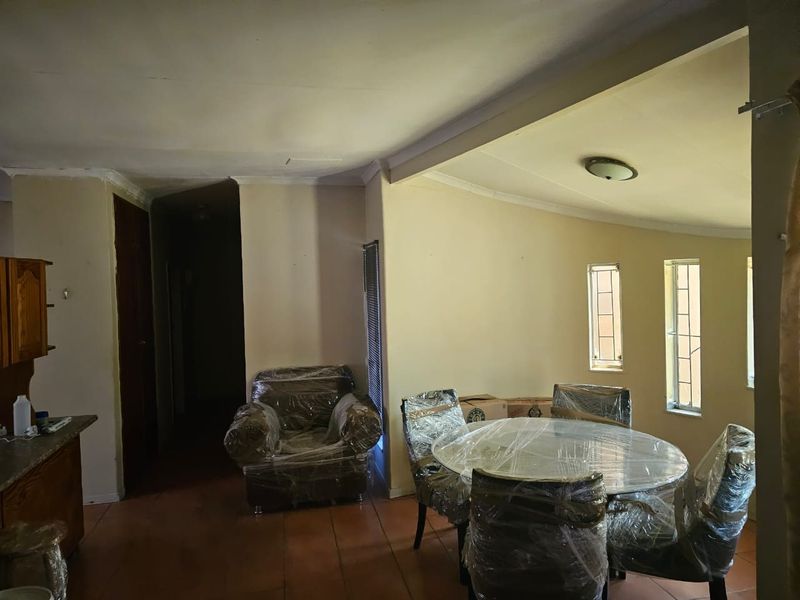 Open plan living and dining area featuring tiled flooring and neutral wall tones, offering a versatile space for renovation and interior design updates.