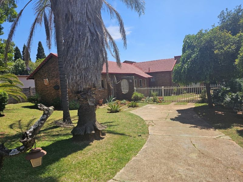 Front view of a face brick house featuring a tiled roof, concrete driveway, and established garden with perimeter fencing.
