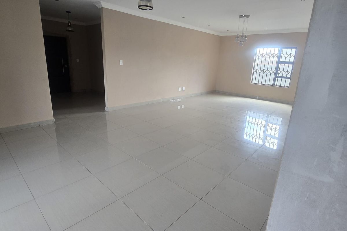 Spacious, open-plan living area featuring neutral wall tones, polished porcelain floor tiles, and modern pendant lighting, ready for custom interior design.