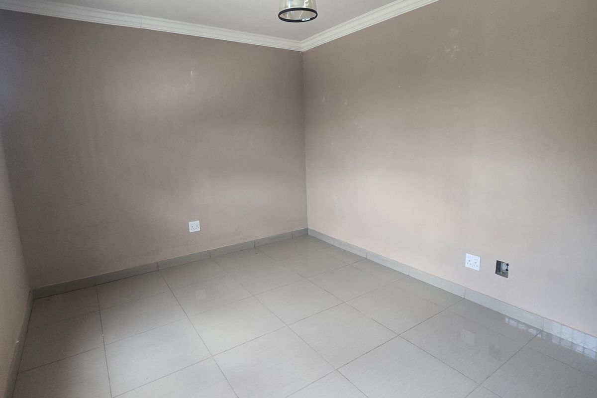 A vacant bedroom featuring neutral wall paint, large format porcelain floor tiles, recessed downlighting, and decorative ceiling cornice.