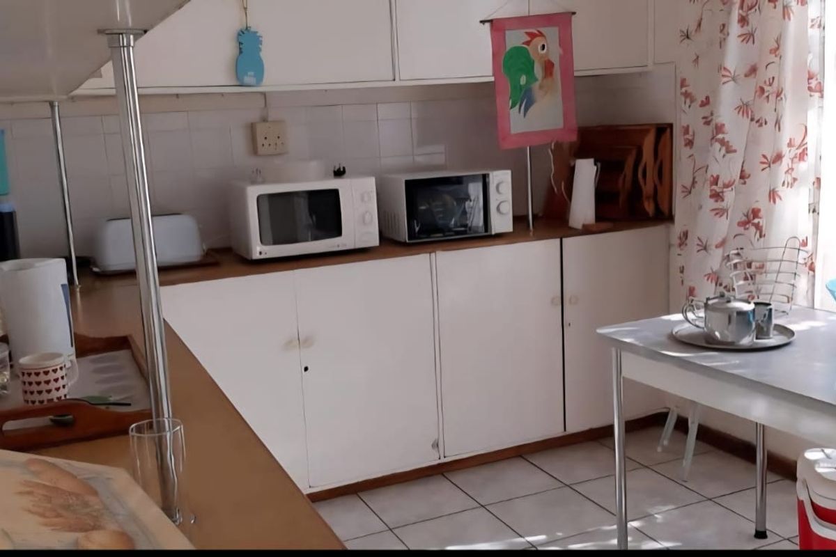A dated kitchen featuring white built-in cabinetry, tiled flooring, and a tiled backsplash, offering a functional layout ready for modernization.