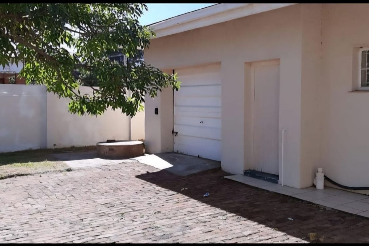 Rear exterior view showing a garage, paved driveway area, and perimeter walling.