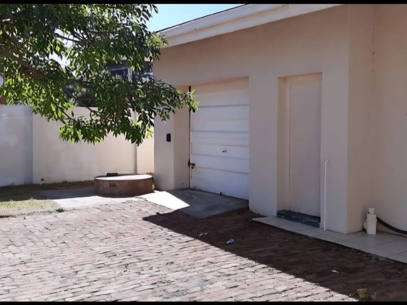 Rear exterior view showing a garage, paved driveway area, and perimeter walling.