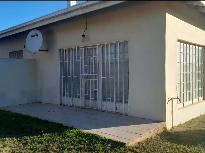 Rear exterior view of the property featuring a tiled patio area, security gates, and window security bars.