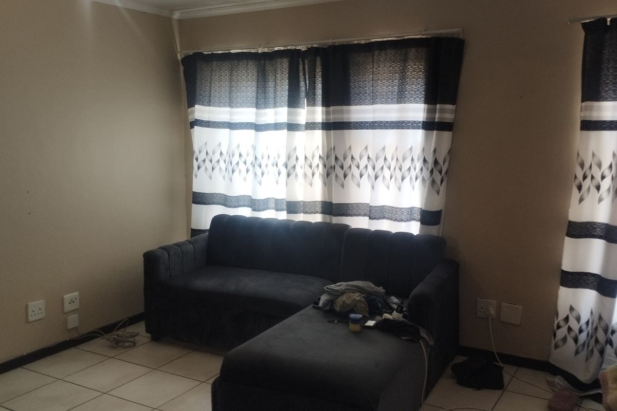 A living room area featuring tiled flooring and large windows with curtain tracks, providing a neutral base for interior design updates.