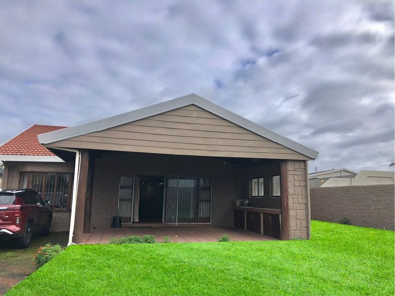 A covered outdoor patio area featuring built-in braai facilities, tiled flooring, and direct access to the interior through sliding doors.