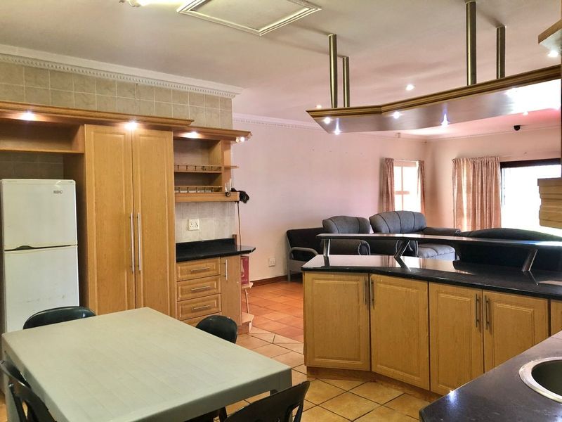 Open-plan kitchen and living area featuring light wood cabinetry, granite countertops, a central island, and tiled flooring throughout.