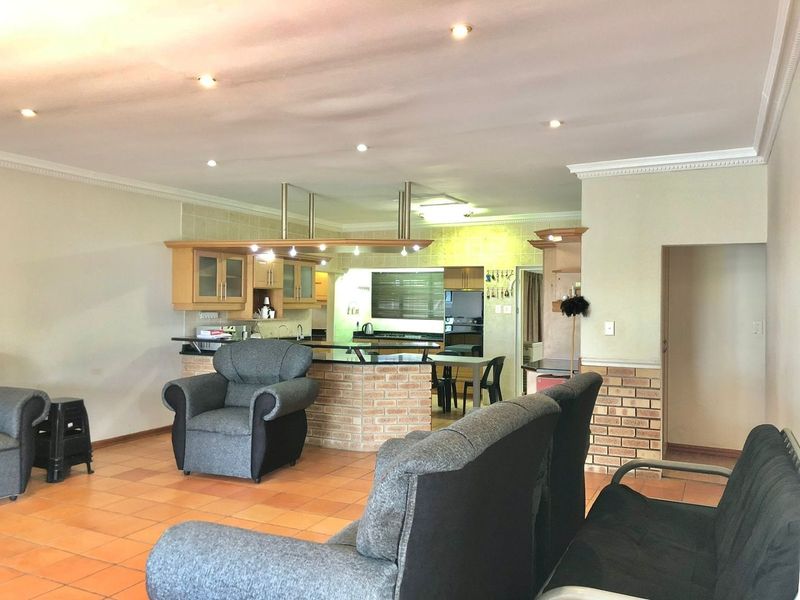 Open plan living and kitchen area featuring tiled flooring, a brick breakfast bar, and recessed lighting throughout the space.