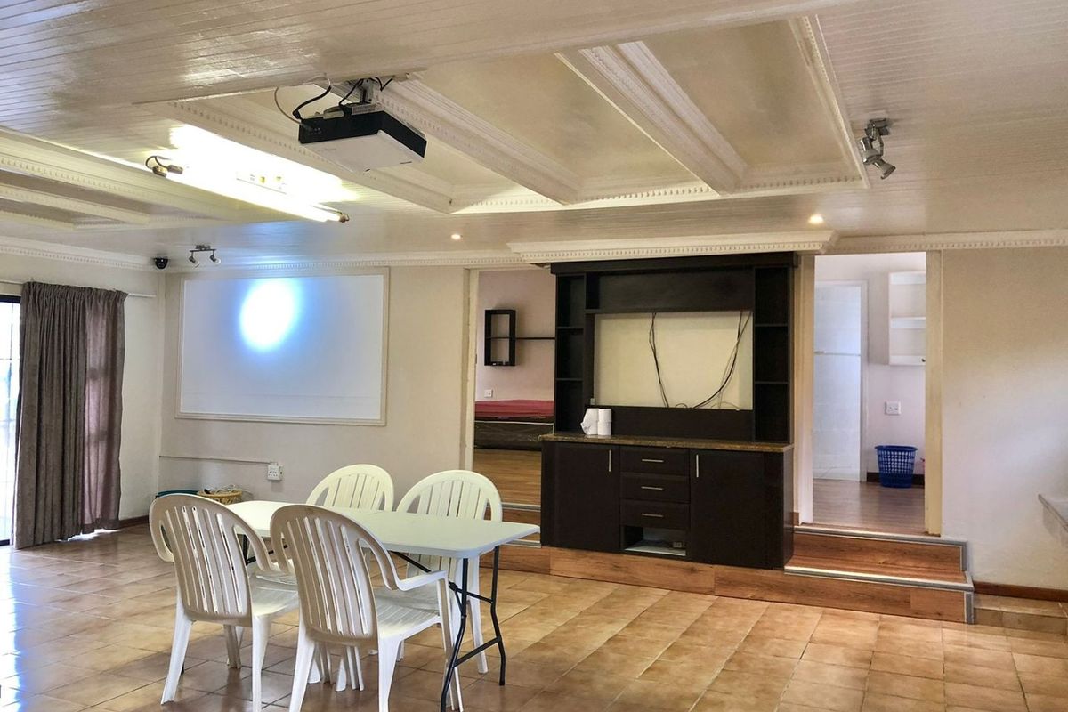 Spacious living area featuring a coffered ceiling, built-in projector and screen, and a raised platform with integrated cabinetry.