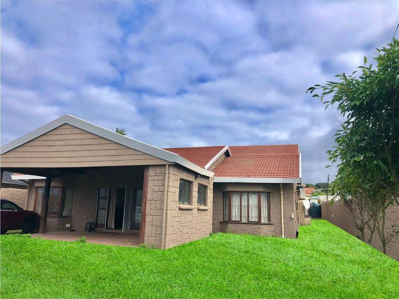 Rear view of the house featuring a covered patio, stone-clad exterior walls, and a well-maintained lawn.