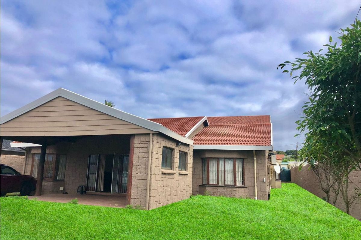Rear view of the house featuring a covered patio, stone-clad exterior walls, and a well-maintained lawn.