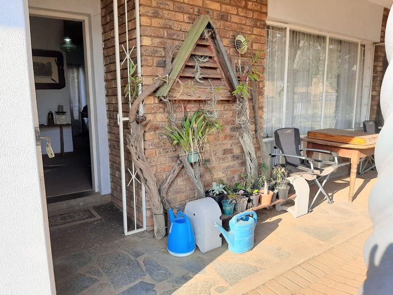 A covered patio area featuring exposed brickwork and stone paving, providing a transition space between the exterior and the home's interior entrance.