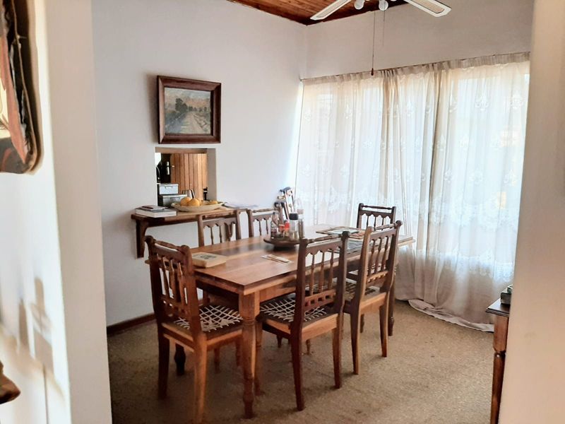 A dining room featuring a timber ceiling, ceiling fan, and a convenient serving hatch connecting to the kitchen area.