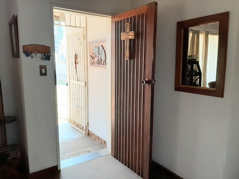 Entrance area featuring a textured timber door and a security gate, providing access to the exterior.