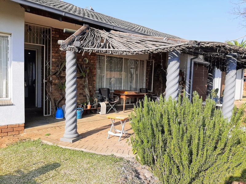 A covered patio area featuring decorative columns and a rustic pergola, providing a shaded outdoor space adjacent to the main house structure.