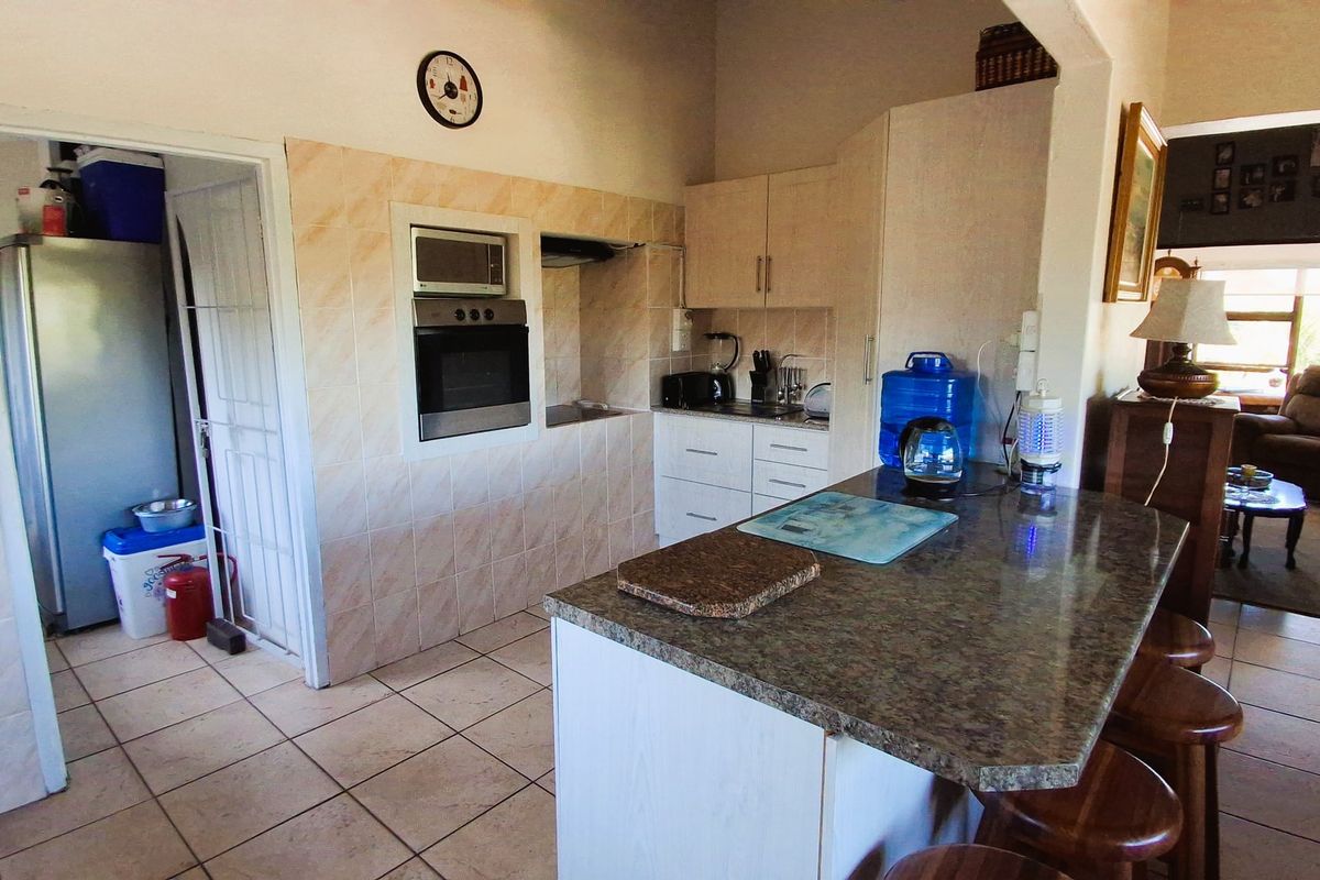 A functional kitchen featuring tiled flooring, granite countertops, built-in oven, and microwave, with an open-plan layout connecting to the adjacent living area.