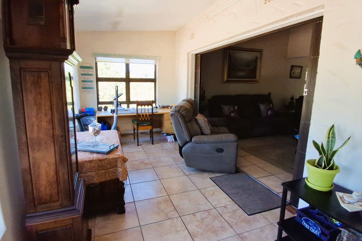 A living area featuring tiled flooring and a sliding room divider, connecting to an adjacent space with natural light from a large window.