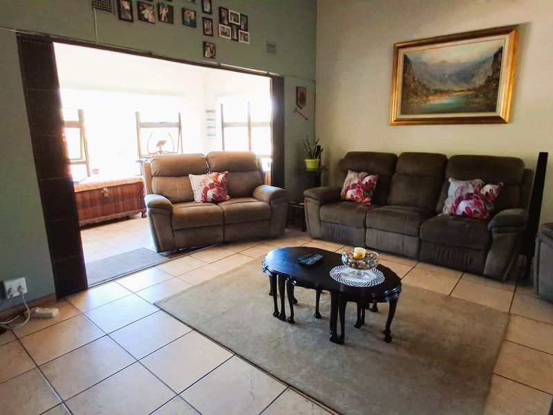 Spacious living room featuring tiled flooring and a large sliding door providing access to an adjacent sunroom area.