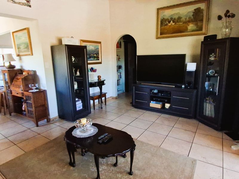 A spacious living room featuring ceramic tile flooring and an arched doorway leading to adjacent living areas.