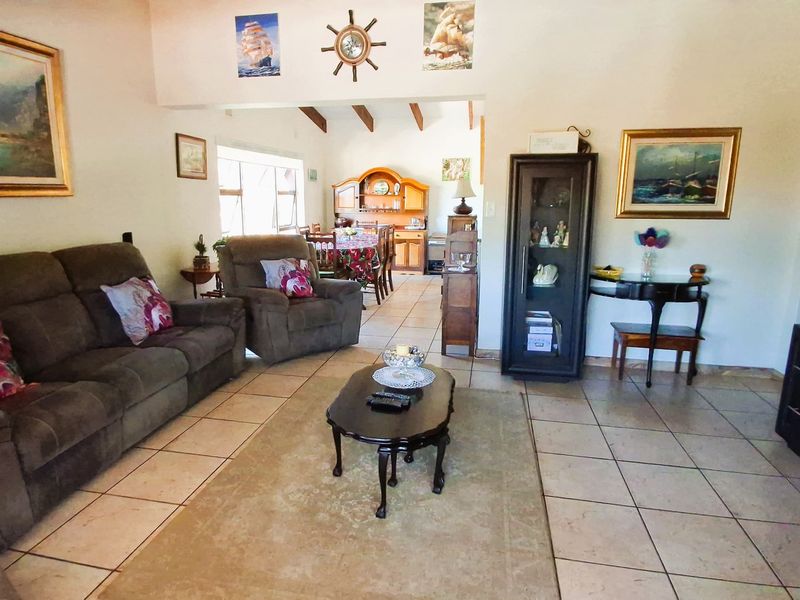 Open-plan living and dining area featuring tiled flooring, exposed timber ceiling beams, and an arched doorway leading to additional space.
