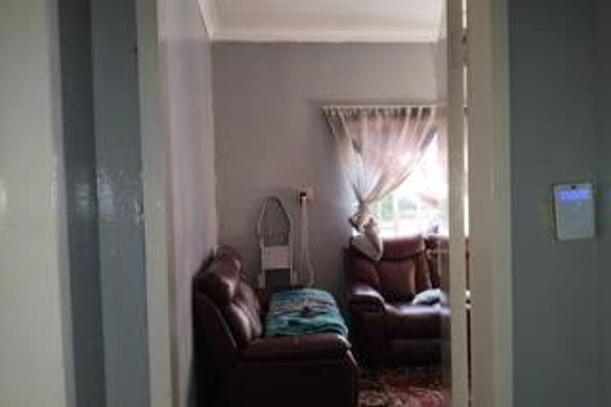 A view into a living room space featuring neutral wall finishes and coving, viewed through a doorway.