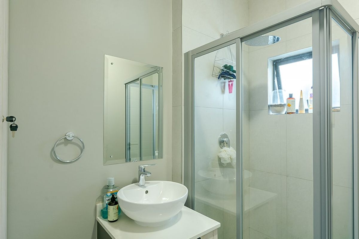 A clean, modern bathroom featuring a glass-enclosed shower, a contemporary vessel sink vanity, and neutral wall tiling.