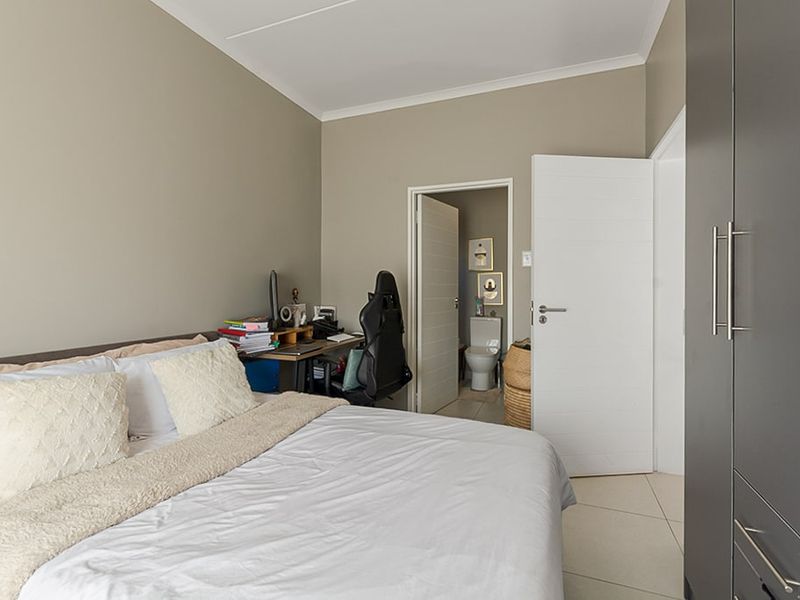 A well-maintained bedroom featuring tiled flooring, a built-in wardrobe, and direct access to an en-suite bathroom.