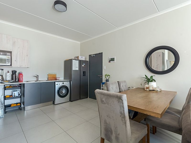 Open-plan living and kitchen area featuring modern grey cabinetry, tiled flooring, and a functional layout suitable for dining and daily living.