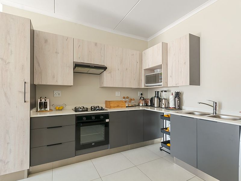 Modern kitchen featuring two-tone cabinetry, stone countertops, built-in oven, gas hob, extractor fan, and a double sink with mixer tap.