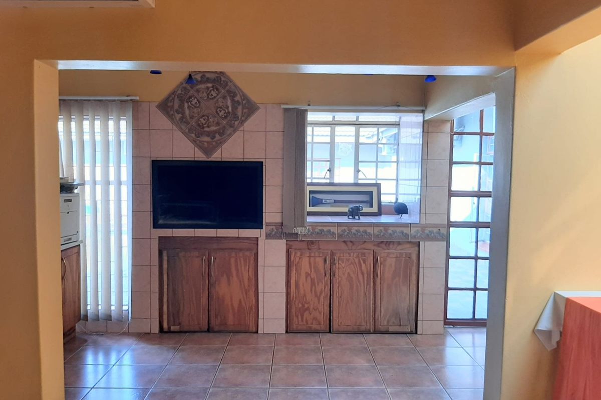 A living area featuring built-in wooden cabinetry, tiled flooring, and a recessed television space, offering a functional layout with natural light.