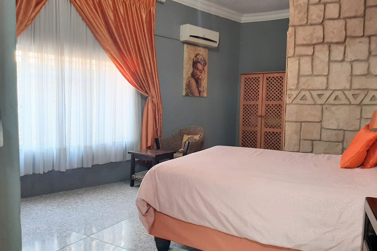 A bedroom featuring a decorative stone-clad feature wall, tiled flooring, and a wall-mounted air conditioning unit.