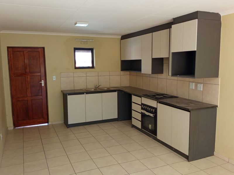 A functional kitchen featuring built-in cabinetry, a double sink, integrated oven and hob, tiled backsplash, and tiled flooring.