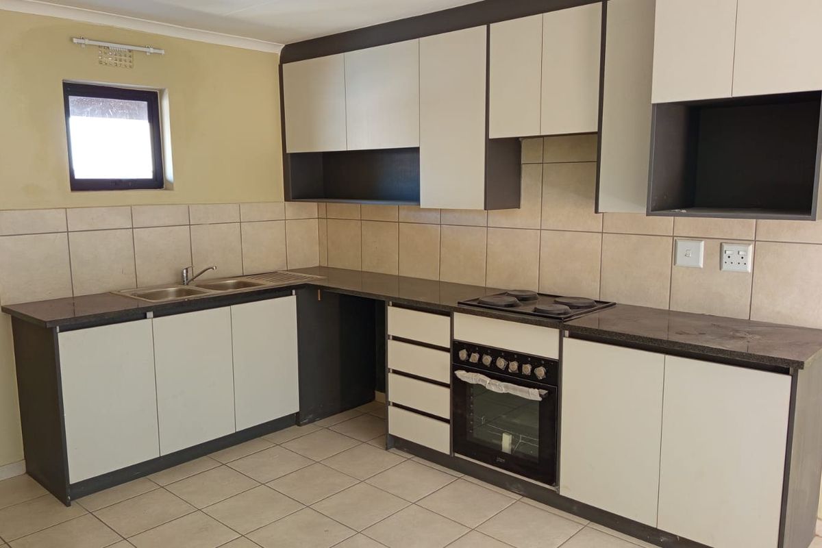 A functional kitchen featuring built-in cabinetry, a double bowl sink, tiled backsplash, and a built-in oven with an electric hob.