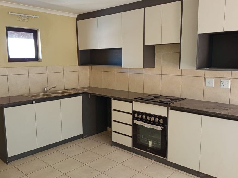 A functional kitchen featuring built-in cabinetry, a double bowl sink, tiled backsplash, and a built-in oven with an electric hob.
