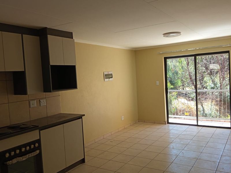 Open-plan kitchen and living area featuring tiled floors, built-in cabinetry, and a sliding glass door leading to a balcony.