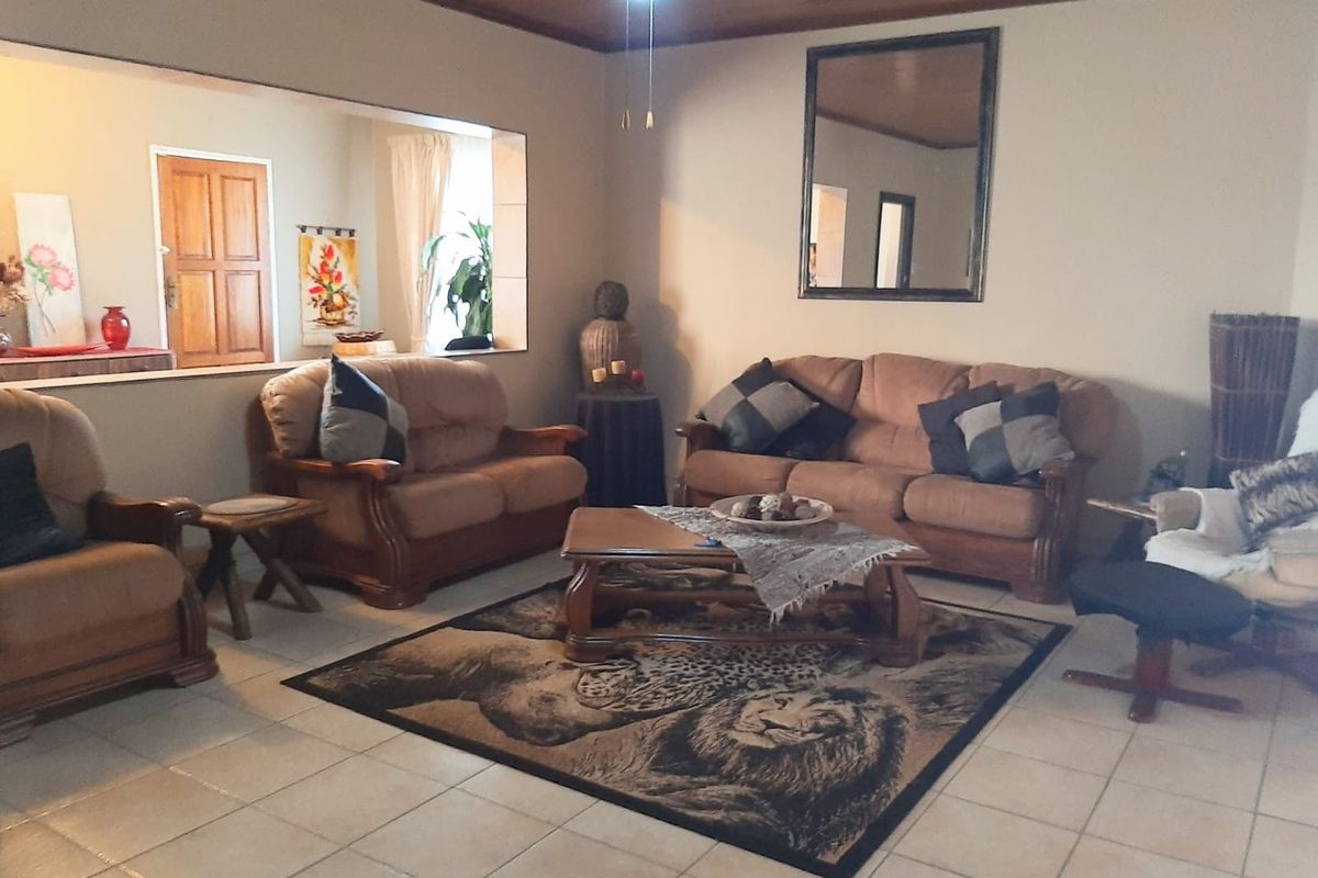 A living room featuring tiled flooring, a timber ceiling with a fan, and a pass-through window connecting to an adjacent space.