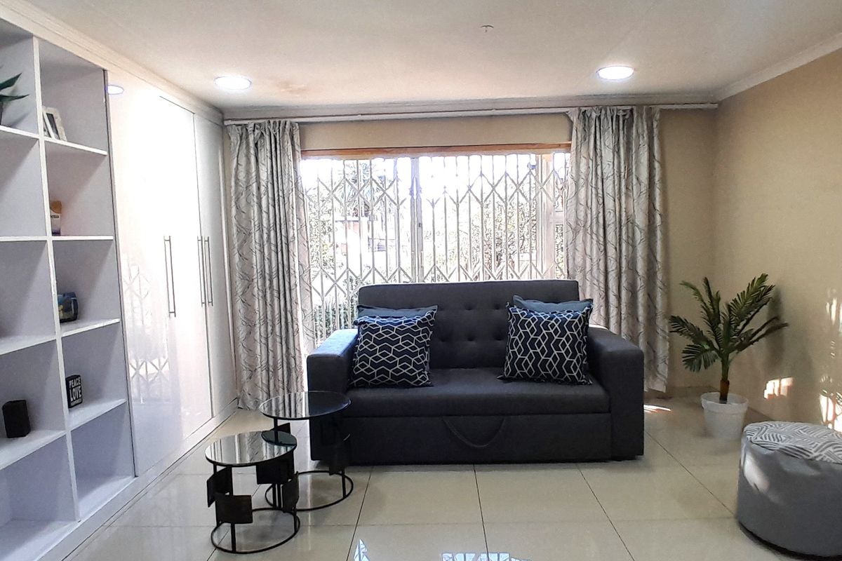 A well-maintained living room featuring tiled flooring, recessed downlighting, and integrated built-in cabinetry for storage.