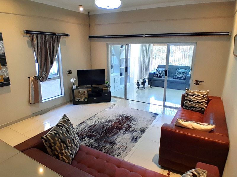 Spacious living room featuring tiled flooring, recessed lighting, and large sliding glass doors that provide access to an adjoining patio area.