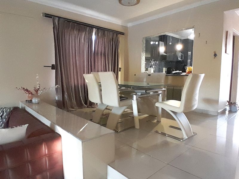 Open-plan living and dining area featuring a sunken lounge, tiled flooring, and a convenient pass-through window connecting to the kitchen space.