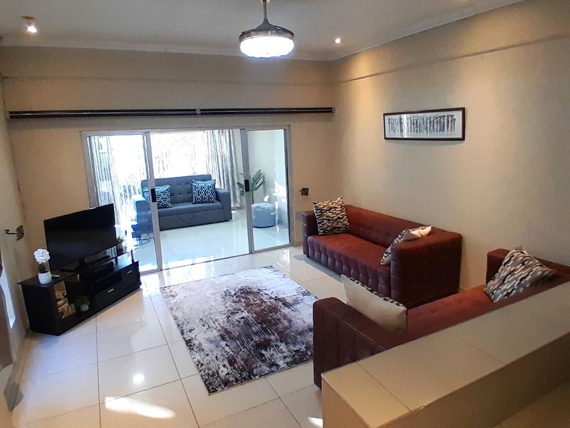 Spacious living room featuring tiled flooring, built-in cabinetry, and large sliding glass doors that provide access to an outdoor patio area.