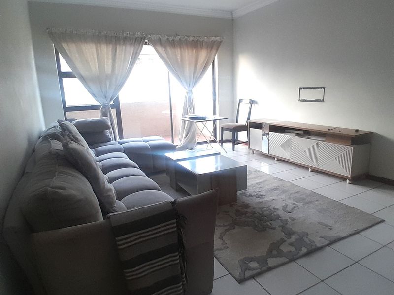 A living room featuring tiled flooring, coved ceilings, and a sliding glass door providing access to an outdoor area.