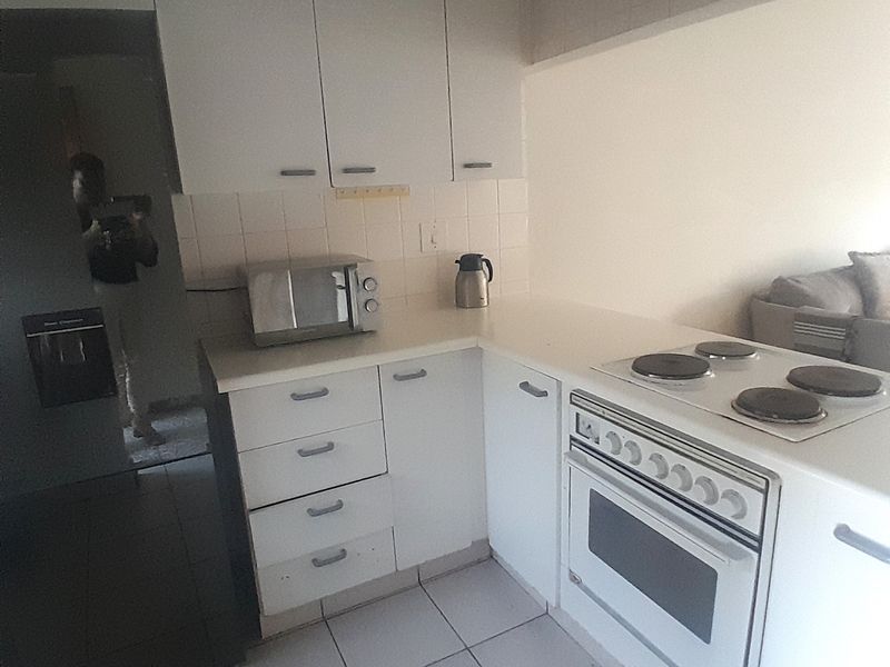 A functional kitchen featuring white cabinetry, tiled flooring, a tiled backsplash, and a built-in electric stove with oven.